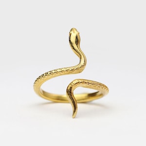 May include: A gold-toned snake ring with a coiled design. The snake's head is raised and the tail is curled around the band.