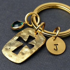 Peut inclure: Porte-clés doré avec un charme en forme de croix, un charme en pierre précieuse verte et un charme rond avec la lettre "J" gravée dessus.