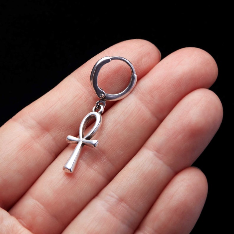 May include: Silver hoop earring with a silver ankh pendant.
