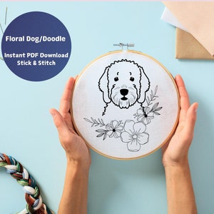 May include: A white embroidery hoop with a black and white line drawing of a doodle dog with floral accents. The text "Floral Dog/Doodle Instant PDF Download Stick & Stitch" is above the hoop.