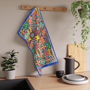 May include: A colorful kitchen towel with a vibrant geometric pattern, featuring red, yellow, blue, and green designs. The towel has a blue border and is hanging on a wooden rack. The towel is made of a soft material.