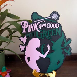 Arte mural 3D del musical Wicked: Glinda y Elphaba, el rosa combina bien con el verde.