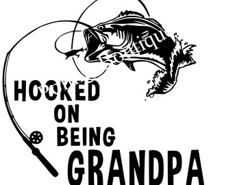 May include: Black and white illustration of a fish jumping out of the water with a fishing rod and reel. The text "HOOKED ON BEING GRANDPA" is below the fish.