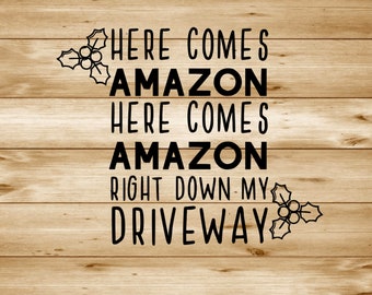 May include: A woodgrain background with a black text overlay that reads "Here comes Amazon here comes Amazon right down my driveway".  The text is flanked by two holly sprigs.