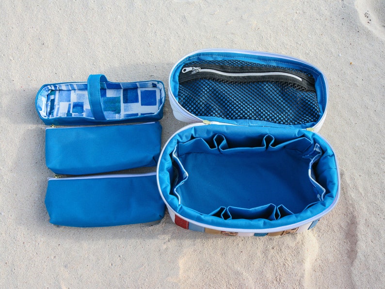 May include: A set of four blue and white zippered pouches, including a large oval-shaped pouch with multiple compartments and a mesh pocket. The pouches are made of fabric and have a white zipper.