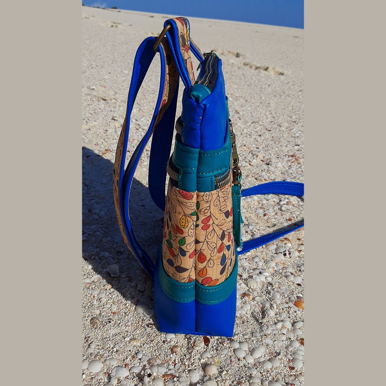 May include: A blue and brown crossbody bag with a floral pattern and multiple zippered compartments.