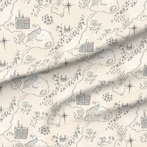 May include: A cream-colored fabric with a repeating pattern of a fantasy map. The map features castles, mountains, trees, rivers, and compass roses, all rendered in a detailed, hand-drawn style. The overall design evokes a sense of adventure and exploration.