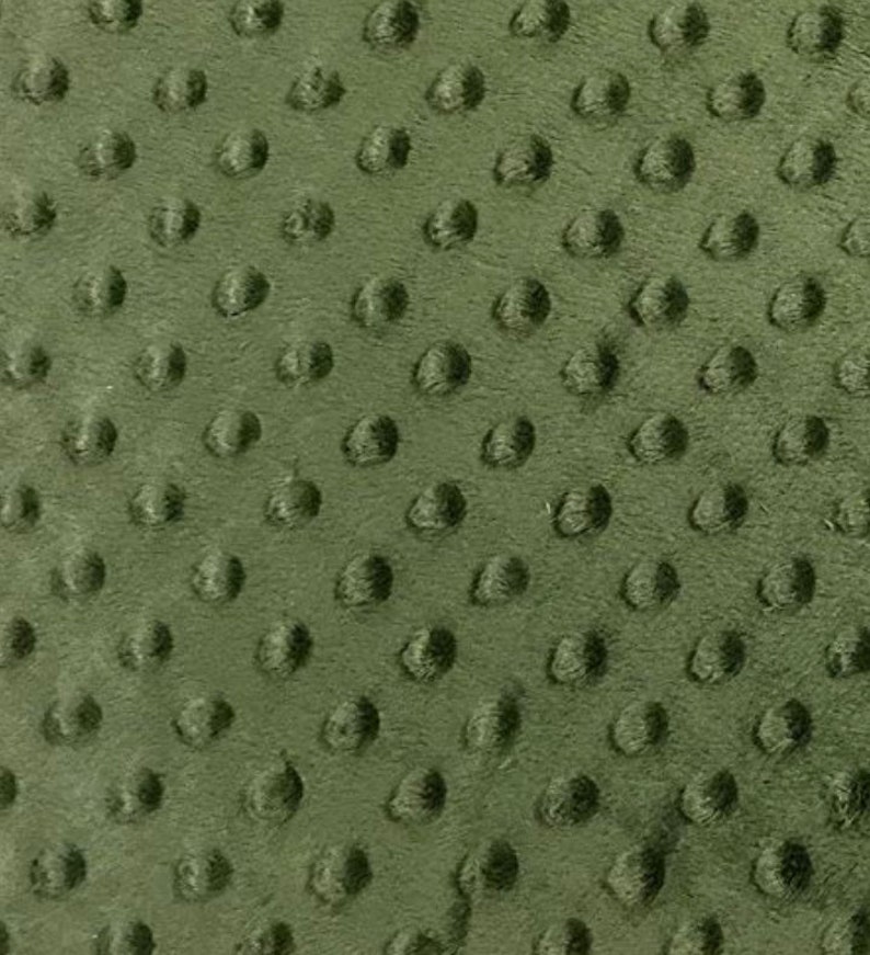 May include: Close-up of olive green fabric with a raised, textured pattern of evenly spaced, rounded bumps. The fabric has a soft, plush appearance, and the texture creates a tactile, three-dimensional effect. The color is a muted, earthy green.