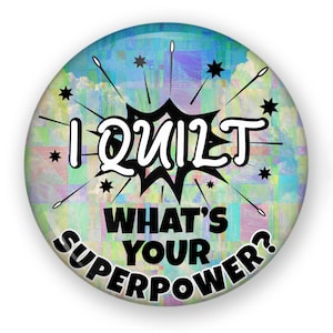 May include: A round button with a colorful background and the text "I Quilt What's Your Superpower?" in black.