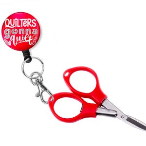 May include: Red retractable badge reel with a red and white button that says "Quilters gonna quilt". A red pair of small scissors is attached to the badge reel.