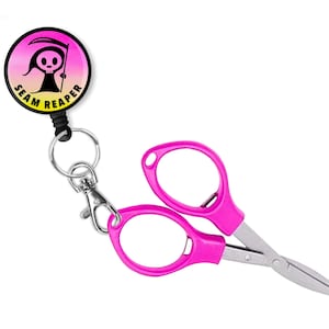 May include: Pink fabric scissors with a black retractable keychain featuring a cartoon grim reaper with the text "Seam Reaper".