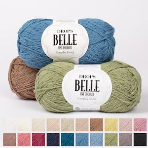 Könnte beinhalten: Drei Knäuel Drops Belle Uni Colour Garn in Blau, Grün und Braun. Die Garnetiketten lauten "Drops Belle Uni Colour Everyday luxury!". Unter den Knäueln wird eine Farbpalette mit Garnmustern angezeigt, die eine Vielzahl von Farben zeigt.