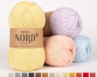 May include: Four skeins of yarn in different colors: yellow, light pink, lavender, and light blue. The yarn is labeled "DROPS NORD* UNI COLOUR Everyday comfort in alpaca and wool."