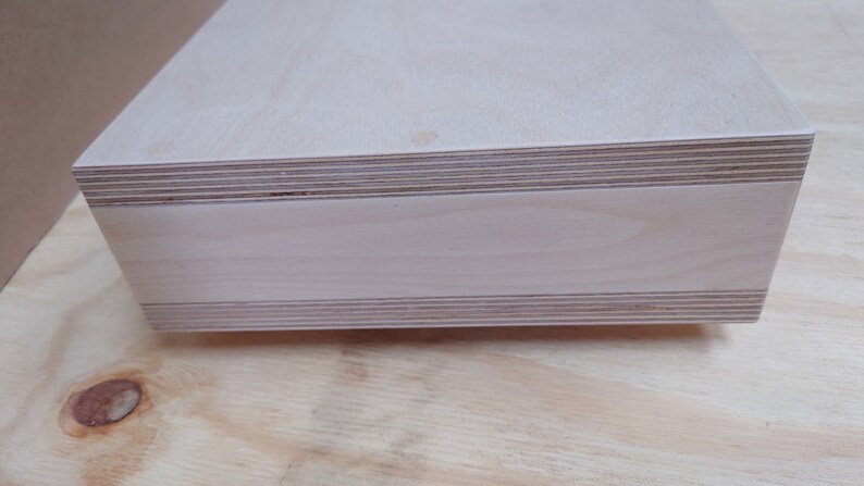 May include: A close-up of the edge of a light wood shelf, showing the layers of plywood.