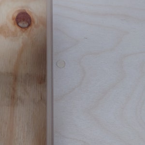 May include: A light wood box with three round wooden plugs on the top.