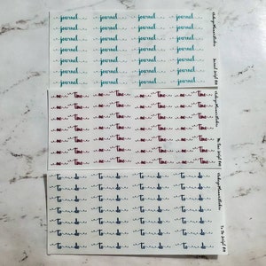 May include: Three sheets of planner stickers with handwritten text. The top sheet has the word "journal" in teal. The middle sheet has the word "time" in burgundy. The bottom sheet has the words "to do" in navy.