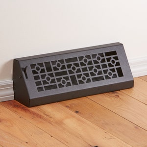 以下が含まれることがあります： 幾何学模様の黒い金属製の床用レジスター。レジスターは角度が付いており、側面に小さなハンドルが付いています。