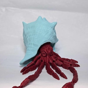 May include: A 3D printed figurine of an octopus emerging from a light blue seashell. The octopus is a deep red color and has eight tentacles.