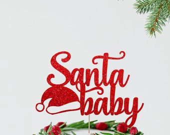 Può includere: Topper per torta di glitter rosso con il testo "Santa Baby" e un cappello di Babbo Natale rosso. Il topper è su una torta bianca con una ghirlanda verde e bacche rosse.