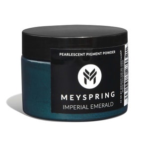 May include: A jar of pearlescent pigment powder labeled "Imperial Emerald" by Meyspring. The jar is dark teal with a black lid and a black label with white text. The label also includes the text "Pearlescent Pigment Powder".