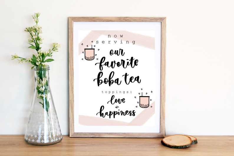 Puede incluir: Una impresi&oacute;n enmarcada con un fondo abstracto rosa y blanco. El texto dice "now serving our favorite boba tea toppings: love & happiness". La impresi&oacute;n presenta dos ilustraciones de tazas de boba tea con pajitas.