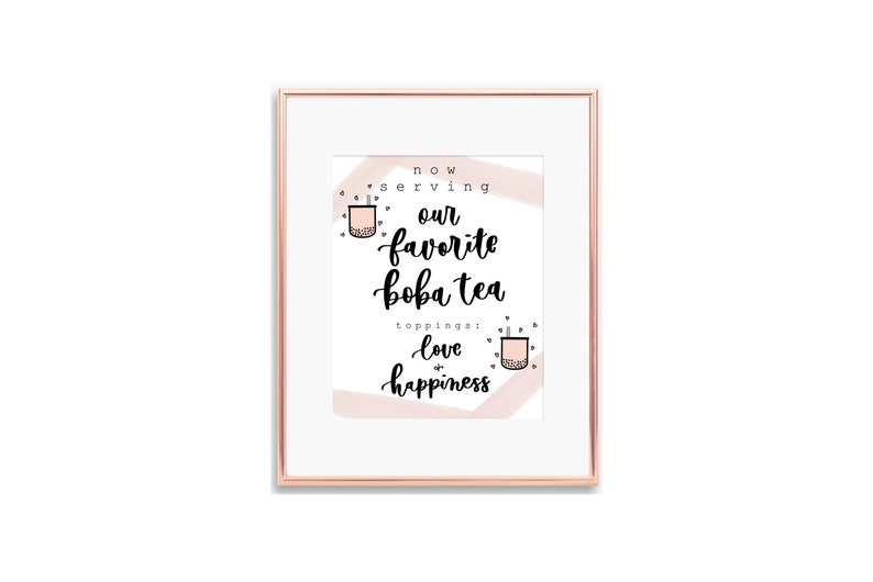 Puede incluir: Una impresi&oacute;n enmarcada en blanco con un fondo rosa y texto negro que dice "Ahora sirviendo nuestra boba tea favorita. Ingredientes: amor y felicidad". La impresi&oacute;n presenta dos ilustraciones de tazas de boba tea.