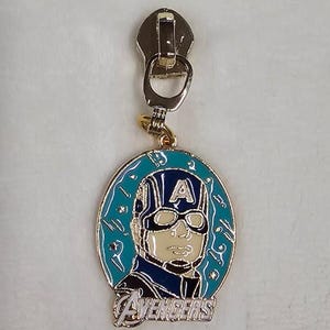 May include: A gold-colored zipper pull with a blue and white enamel charm featuring Captain America's face and the word "AVENGERS".