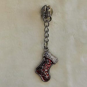 May include: Silver zipper pull with a red and white Christmas stocking charm.