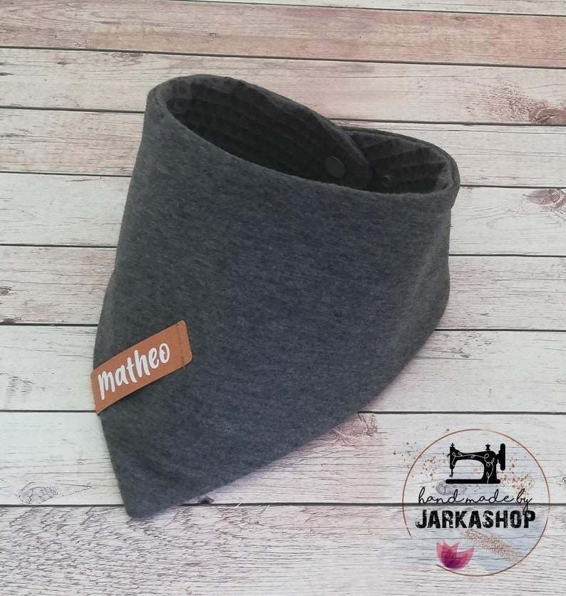 May include: Gray bandana bib with a brown leather label that says "matheo" and a snap closure. Handmade by Jarkashop.