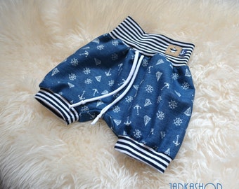 May include: Blue denim shorts with a white and black striped waistband and white anchor and ship wheel print.