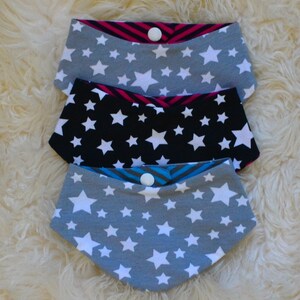Puede incluir: Tres baberos de tela gris y negro con estrellas blancas. Los baberos tienen un cierre a presión y son reversibles.