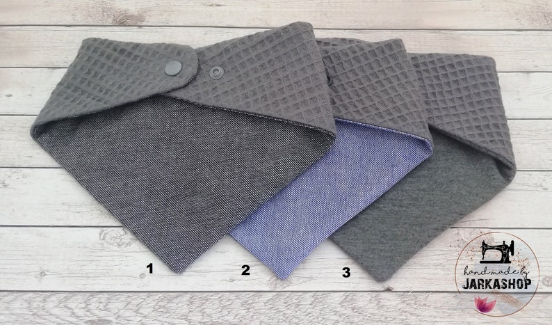 May include: Three reversible fabric squares with different patterns. The first square is gray with a waffle texture on one side and a gray and white patterned fabric on the other side. The second square is gray with a waffle texture on one side and a blue denim fabric on the other side. The third square is gray with a waffle texture on one side and a solid gray fabric on the other side.