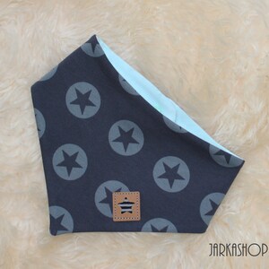 May include: A dark blue bandana with a light blue border and a pattern of white stars in circles. A small brown label with a white star and stripes is in the centre of the bandana.