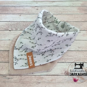 Könnte beinhalten: Ein hellbraunes und weißes Bandana mit einem Blumenmuster und einem braunen Lederanhänger mit der Aufschrift "Jannis". Das Bandana ist handgefertigt von Jarkashop.
