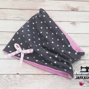 Peut inclure: Un bandeau en tissu à pois noirs et blancs avec une doublure en tissu rose et un nœud rayé rose et blanc.