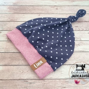 Può includere: Un berretto per neonato blu e rosa con pois bianchi e un'etichetta marrone che dice "Lina". Il berretto ha un nodo sulla parte superiore ed è fatto a mano da Jarkashop.