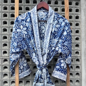 May include: A blue and white floral print robe with a long sleeve and a tie belt.