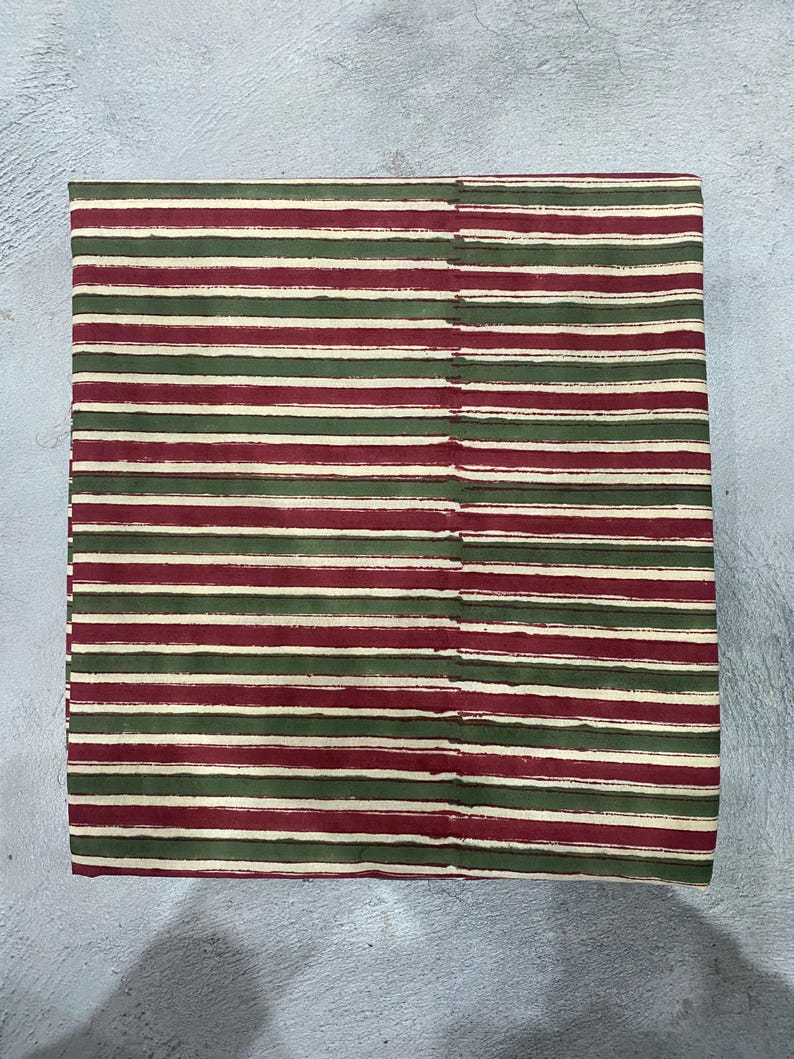 May include: Red and green striped fabric with a white background. The fabric is woven and has a subtle texture.
