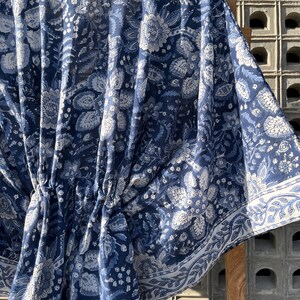 Puede incluir: Una kaftan de algod&oacute;n con estampado floral azul y blanco, con cintura fruncida y un borde alrededor de los bordes.
