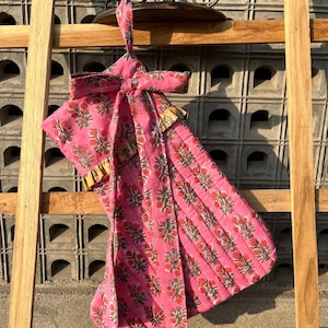 Op de afbeelding: Een roze en groene kerstsok met bloemenprint, gele ruche en bijpassende strik.