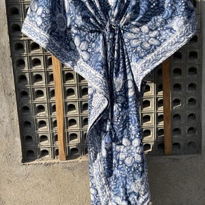 Puede incluir: Una kaftan con estampado azul y blanco, cuello en V y un lazo en la cintura.