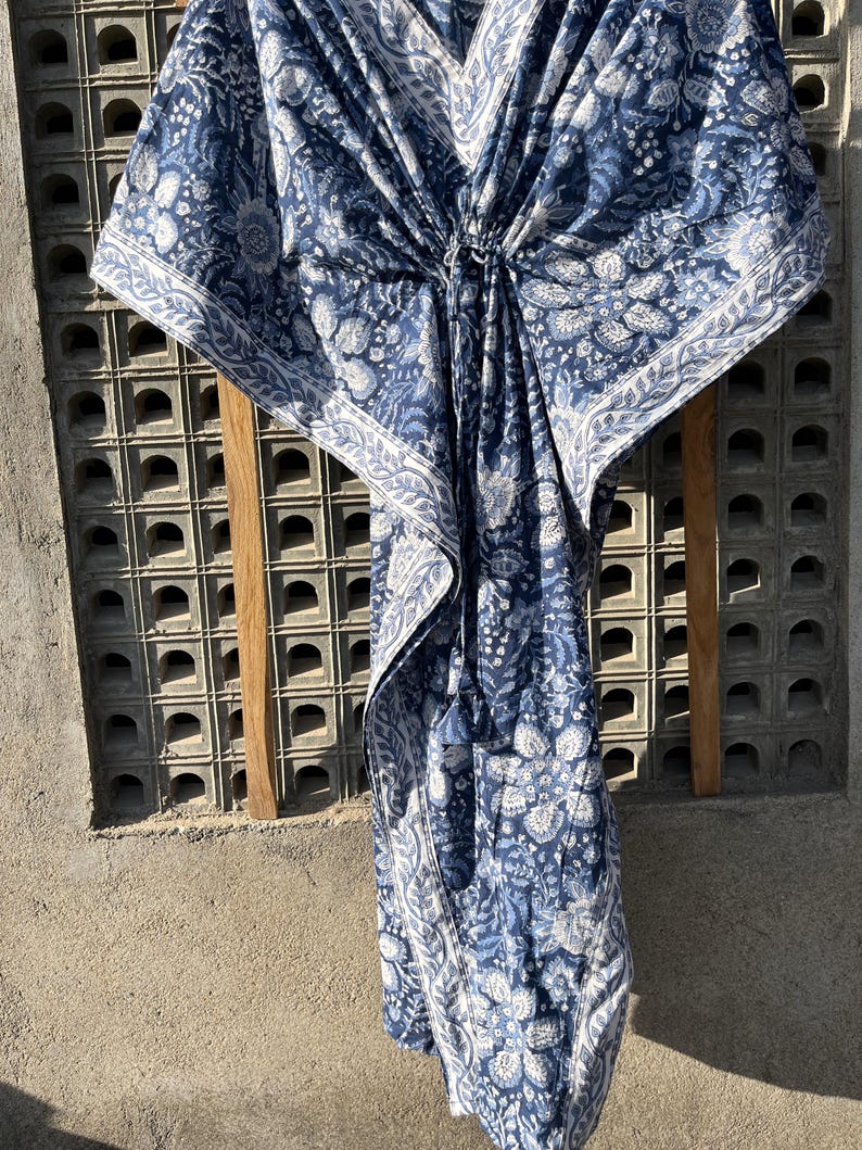Puede incluir: Una kaftan con estampado azul y blanco, cuello en V y un lazo en la cintura.