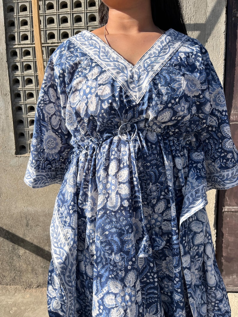 Puede incluir: Una kaft&aacute;n de estampado floral azul y blanco con cuello en V y cintura con cord&oacute;n.