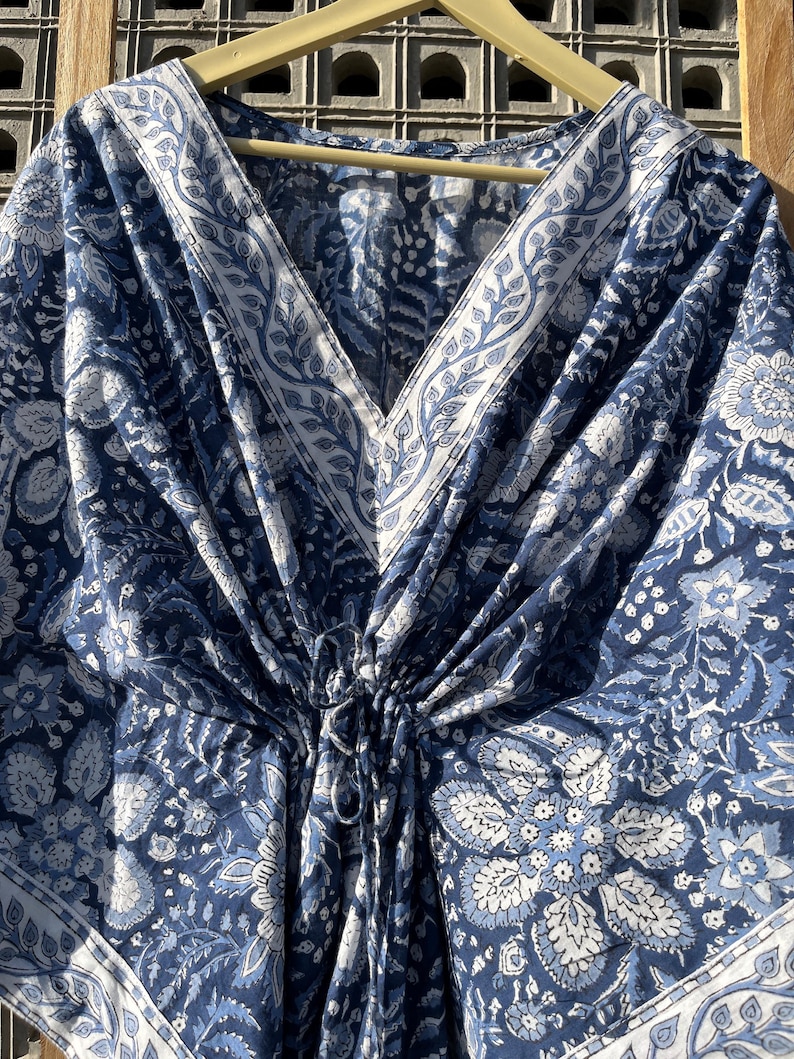 Puede incluir: Una kaft&aacute;n de algod&oacute;n azul y blanco con estampado floral y cuello en V. La kaft&aacute;n tiene una cintura con cord&oacute;n y un ajuste holgado.