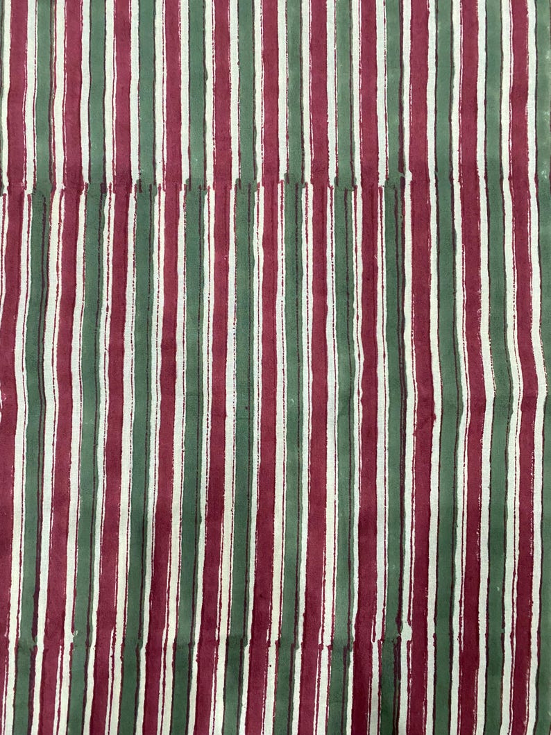 May include: A fabric with alternating vertical stripes of red, green, and white.