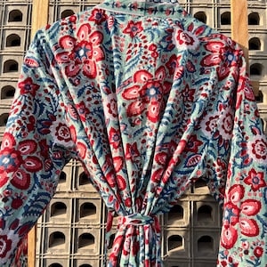 May include: A blue and red floral print robe with a tie waist. The robe is made of a soft, lightweight fabric and is perfect for lounging around the house.