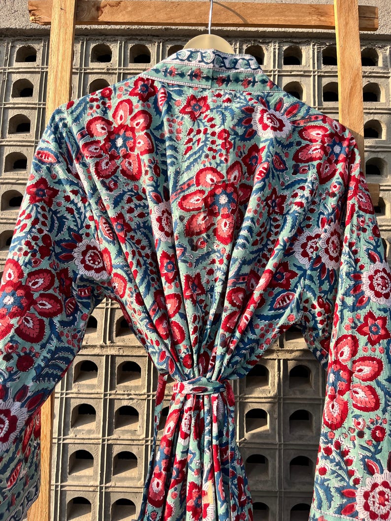May include: A blue and red floral print robe with a tie waist. The robe is made of a soft, lightweight fabric and is perfect for lounging around the house.