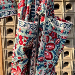 May include: A blue and red floral print fabric with a white trim. The fabric is folded and tied with a white ribbon.