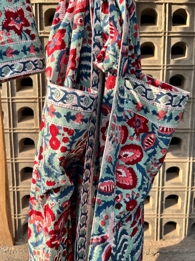 May include: A blue and red floral print fabric with a white trim. The fabric is folded and tied with a white ribbon.