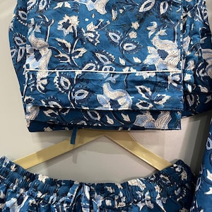 May include: A blue and white floral print pajama set with a drawstring waist and a white trim. The fabric is soft and comfortable.